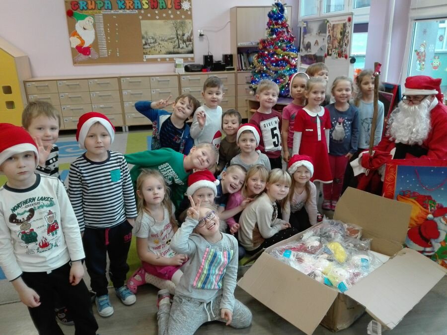 Dzieci witają w grupie Mikołaja oraz otwierają przyniesione prezenty.