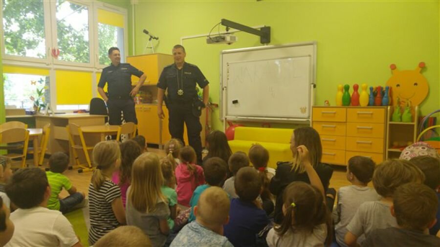 Dzieci biorą udział w prelekcji z panami policjantami dotyczącej bezpiecznych wakacji