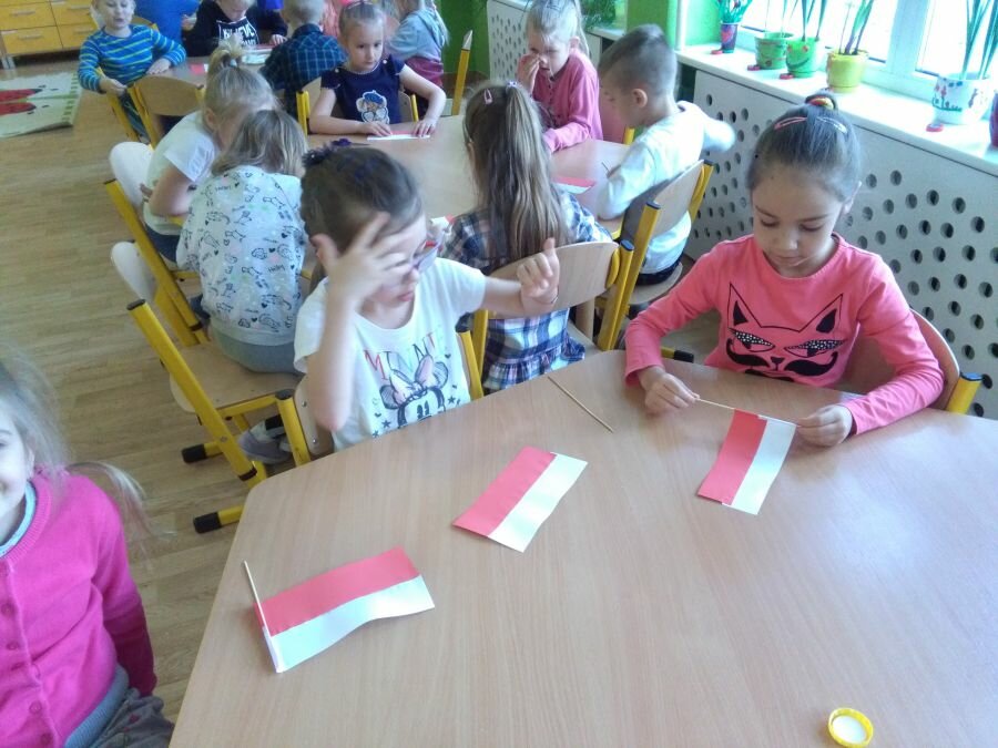 Dzieci wykonują flagi Polski.