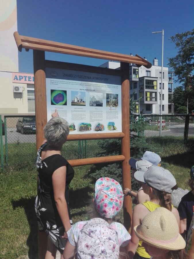 Rozmowa nauczycielki z dziećmi przy tablicy ekologicznej.